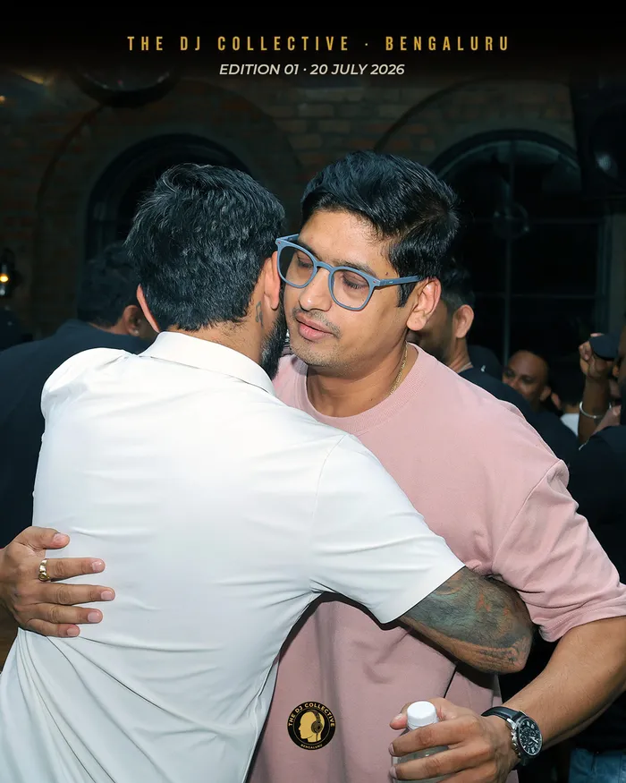 Two DJs greeting each other with a hug in the middle of the room