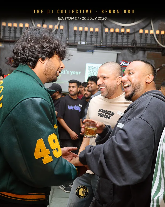 Three DJs laughing together, drinks in hand