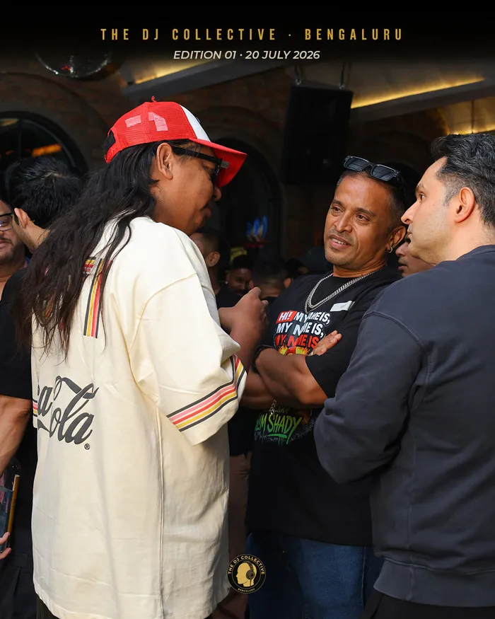 Three people talking near the speakers, one in a red cap
