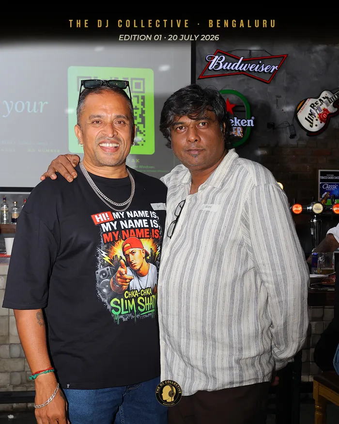 Two DJs arm in arm in front of the bar