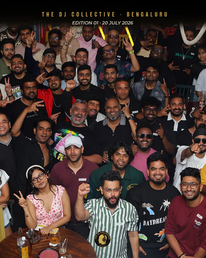 A large group packed together for a photo, arms raised