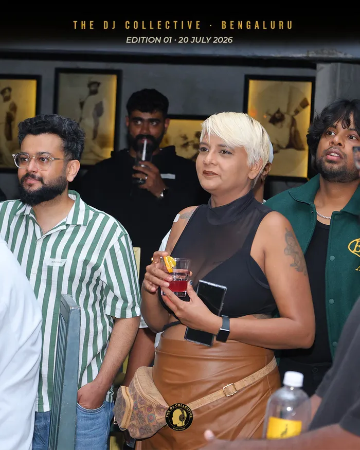 Three people standing and talking, drinks in hand