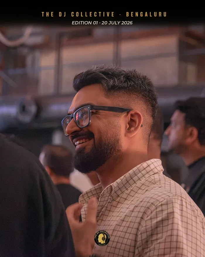 A DJ in glasses smiling in profile amid the crowd