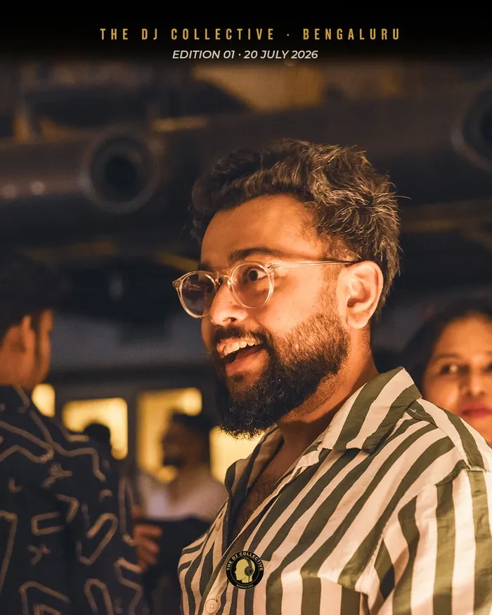 A DJ in a striped shirt and glasses smiling in the crowd