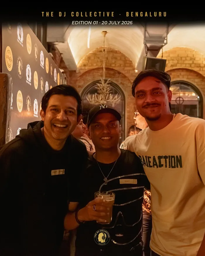 Three friends posing together, drinks in hand
